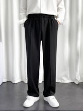 Model wearing URBAN WOLFS men's black baggy joggers with elastic waist straight wide legs and white sneakers